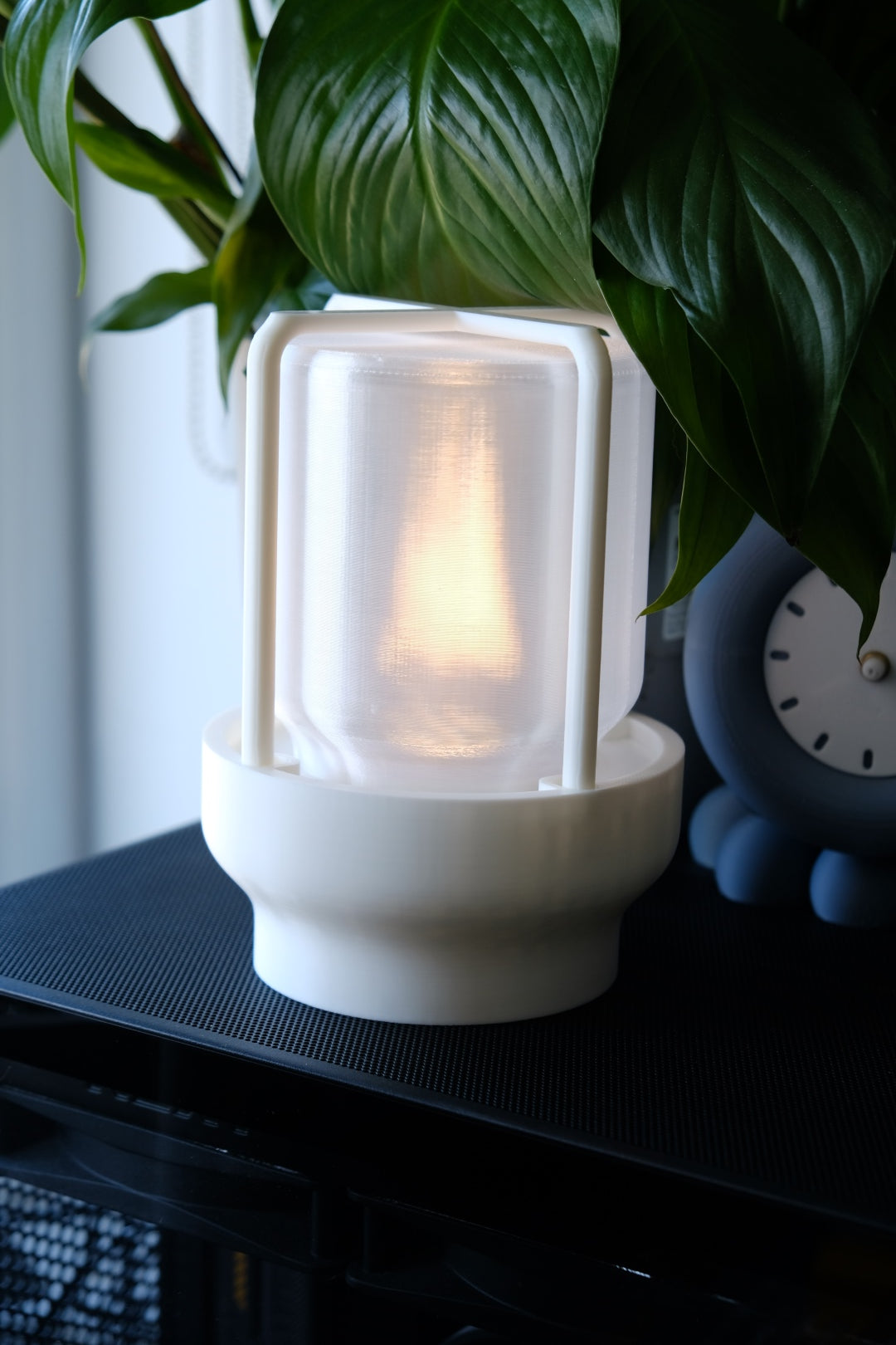 The Miner's Lantern Lamp real photo white on black speaker beside clock and peace lily plant warm amber glow dramatic