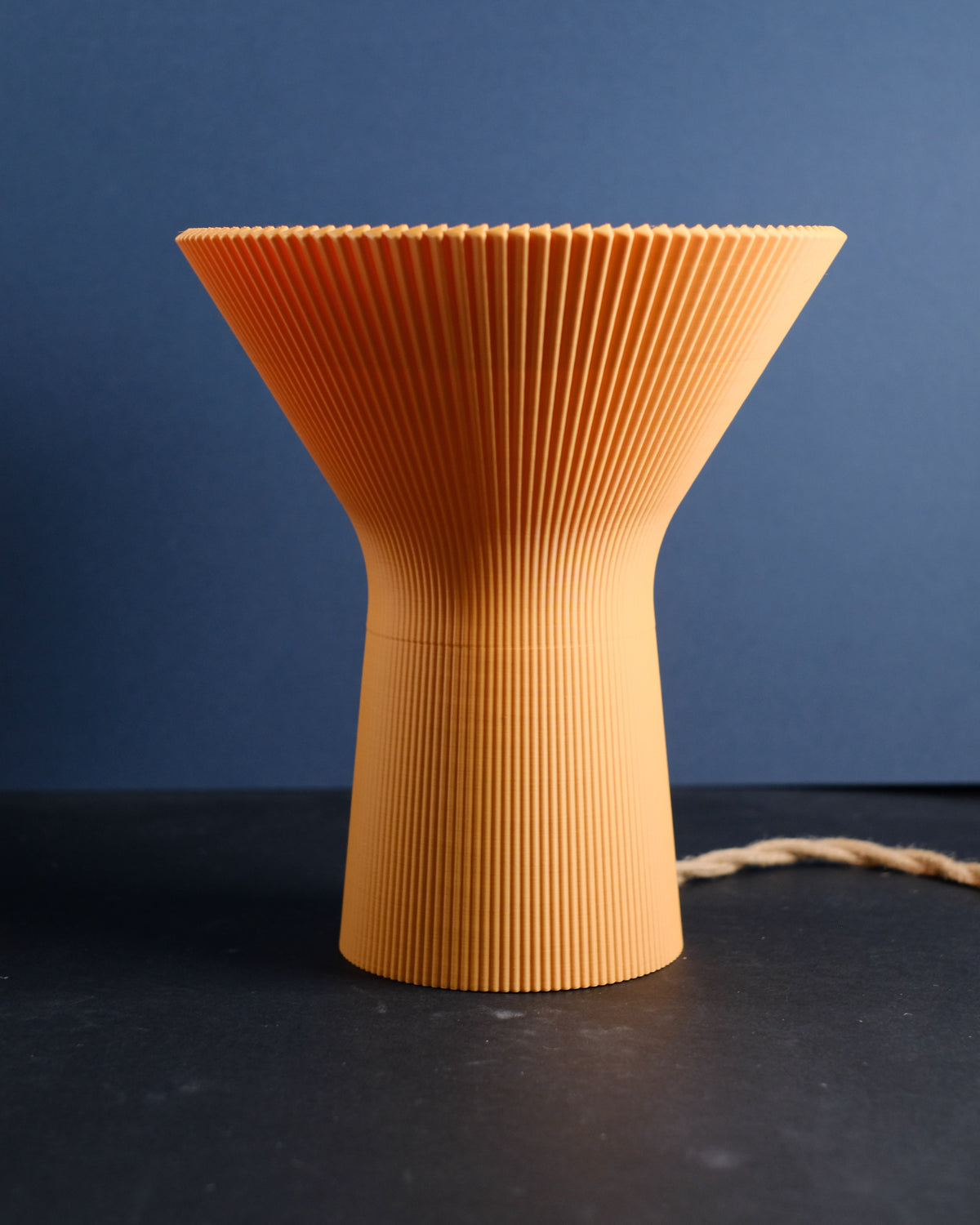 Person holding the orange inverted funnel lamp to show its sculptural shape.