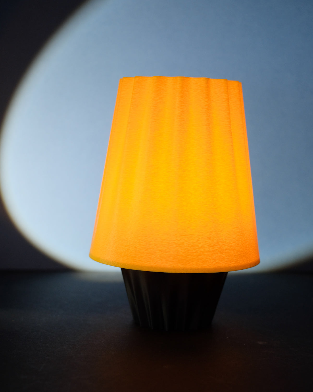 Fluted ambient desk lamp with black base held in a hand
