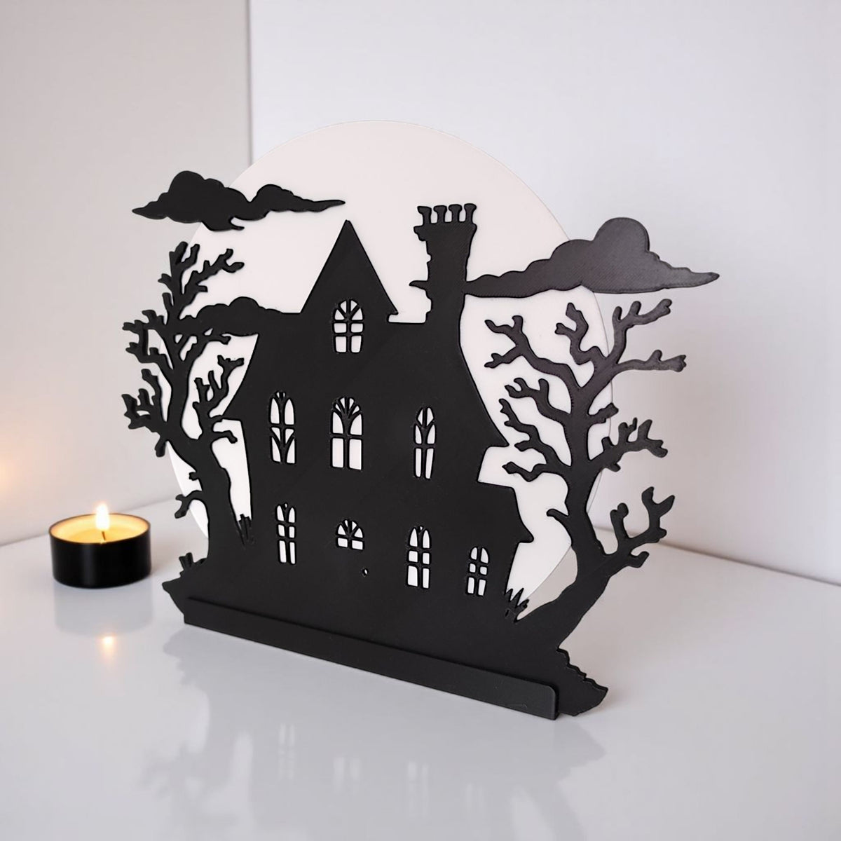 Haunted house decoration glowing amber at night with full moon outside window