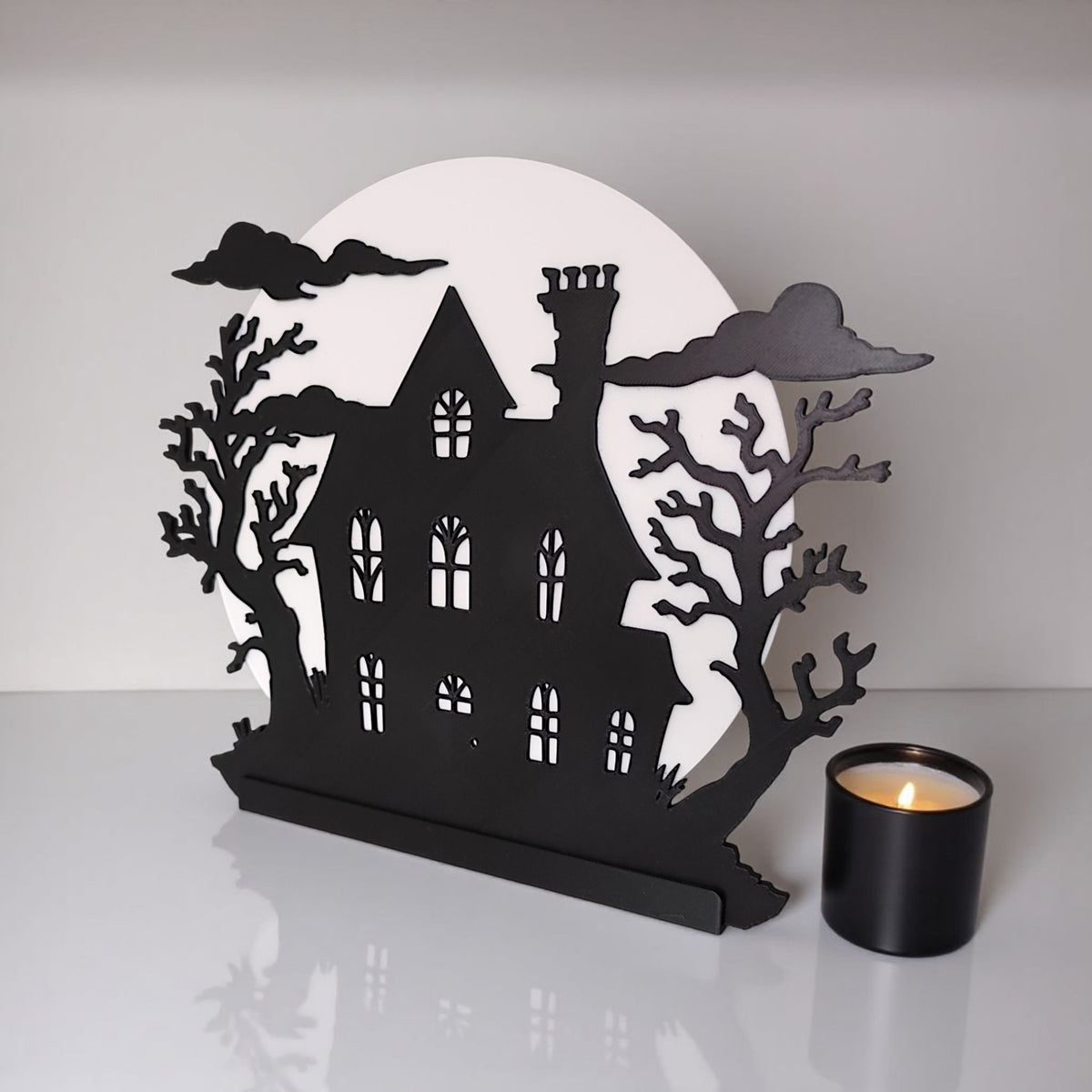 Haunted house decoration with warm LED glow on white surface with pumpkin and candy corn