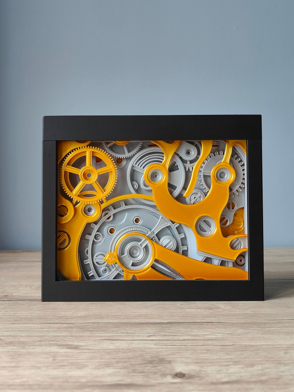 Clockwork shadow box - front view with gold and silver gear mechanism in black frame