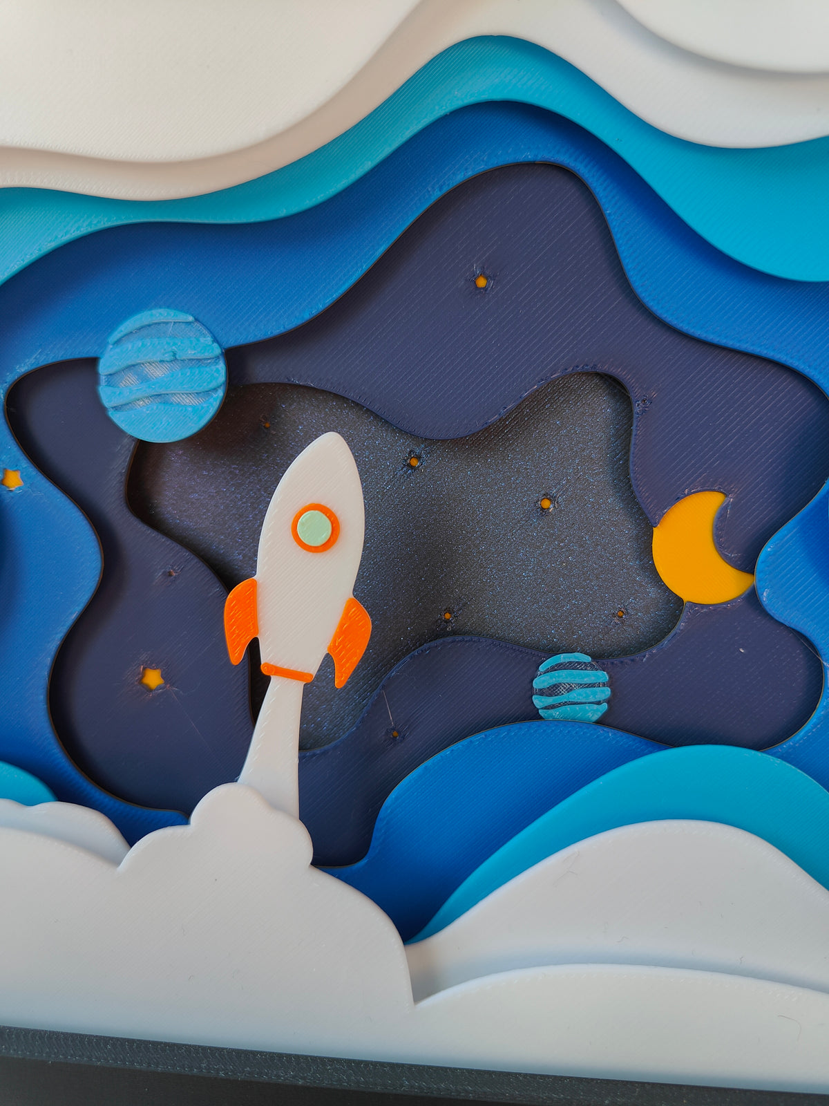 Space shadow box - close up of white rocket, blue planet, golden moon and twinkling stars