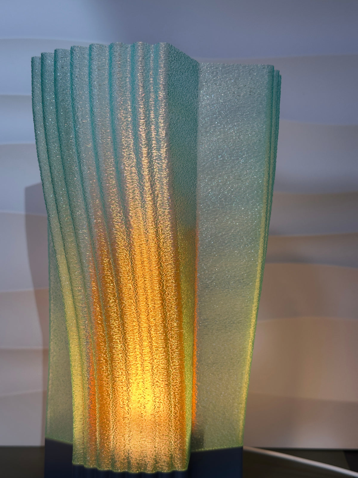 Swirl and Shine Desk Lamp real photo close up macro detail ribbed twisted surface catching warm glow dark background