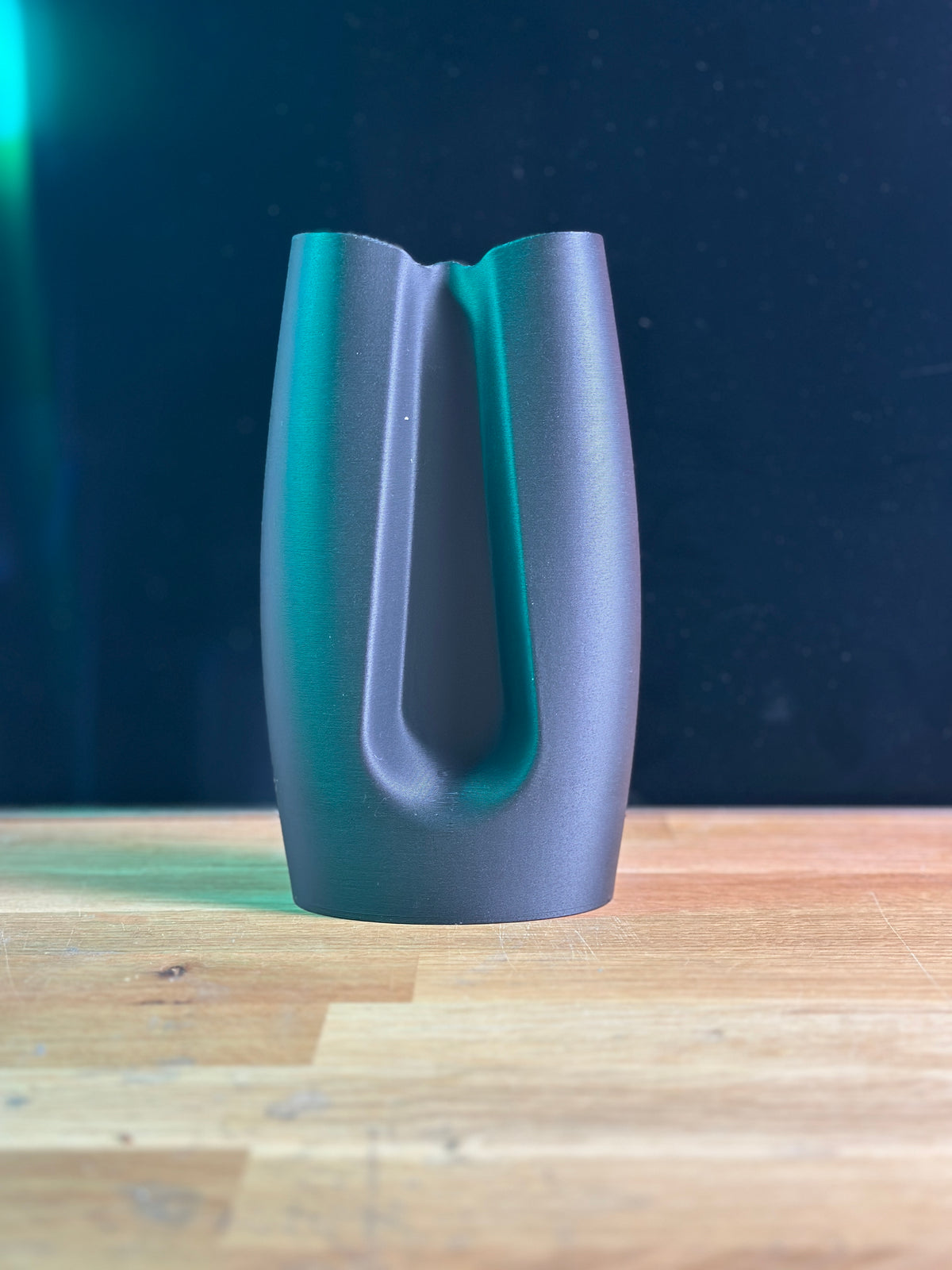 Modern Curved Minimalist Vase dark grey real product on wooden table dark background wider view