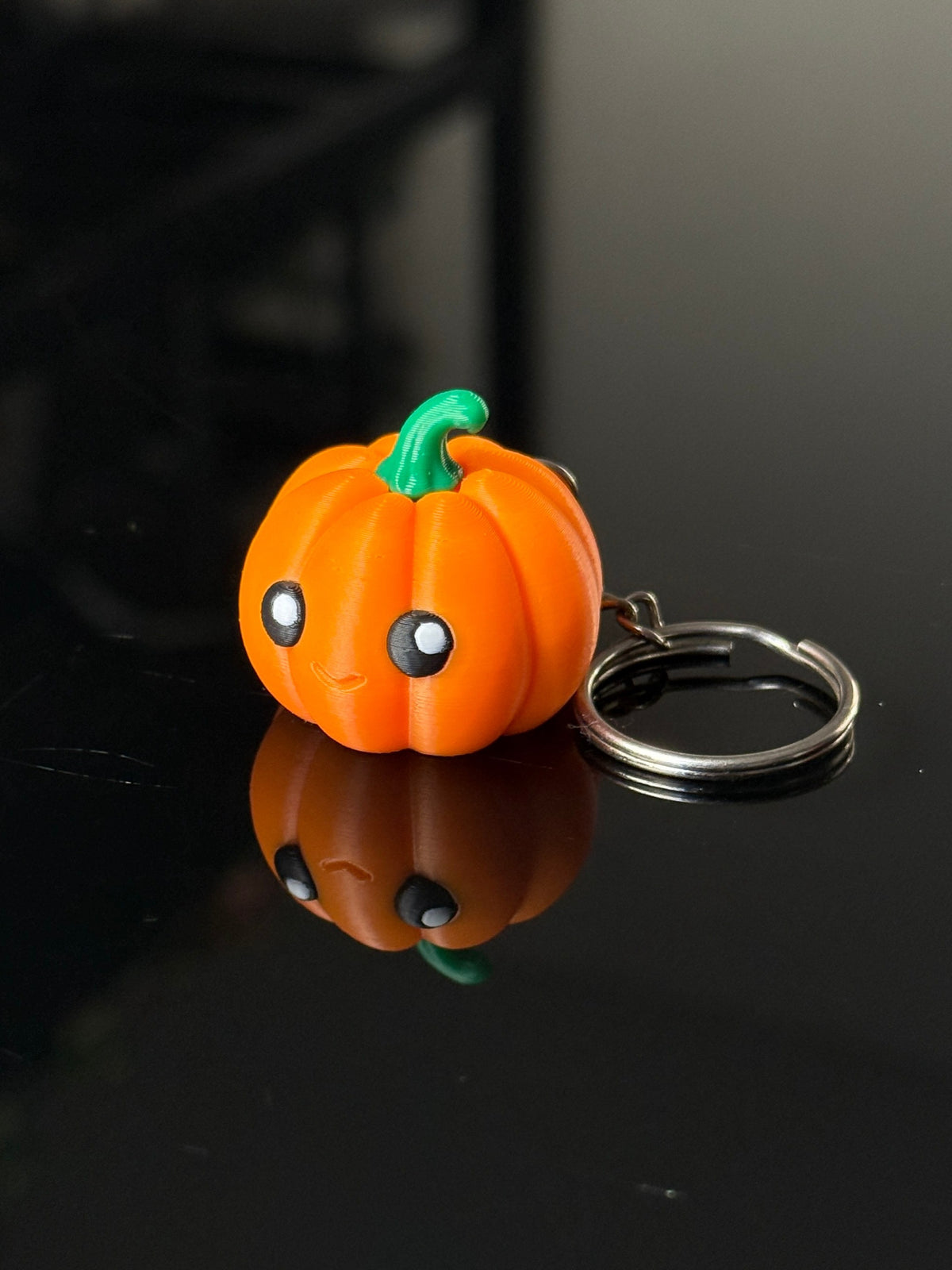 Mini Pumpkin Keychain Clicker on reflective black table