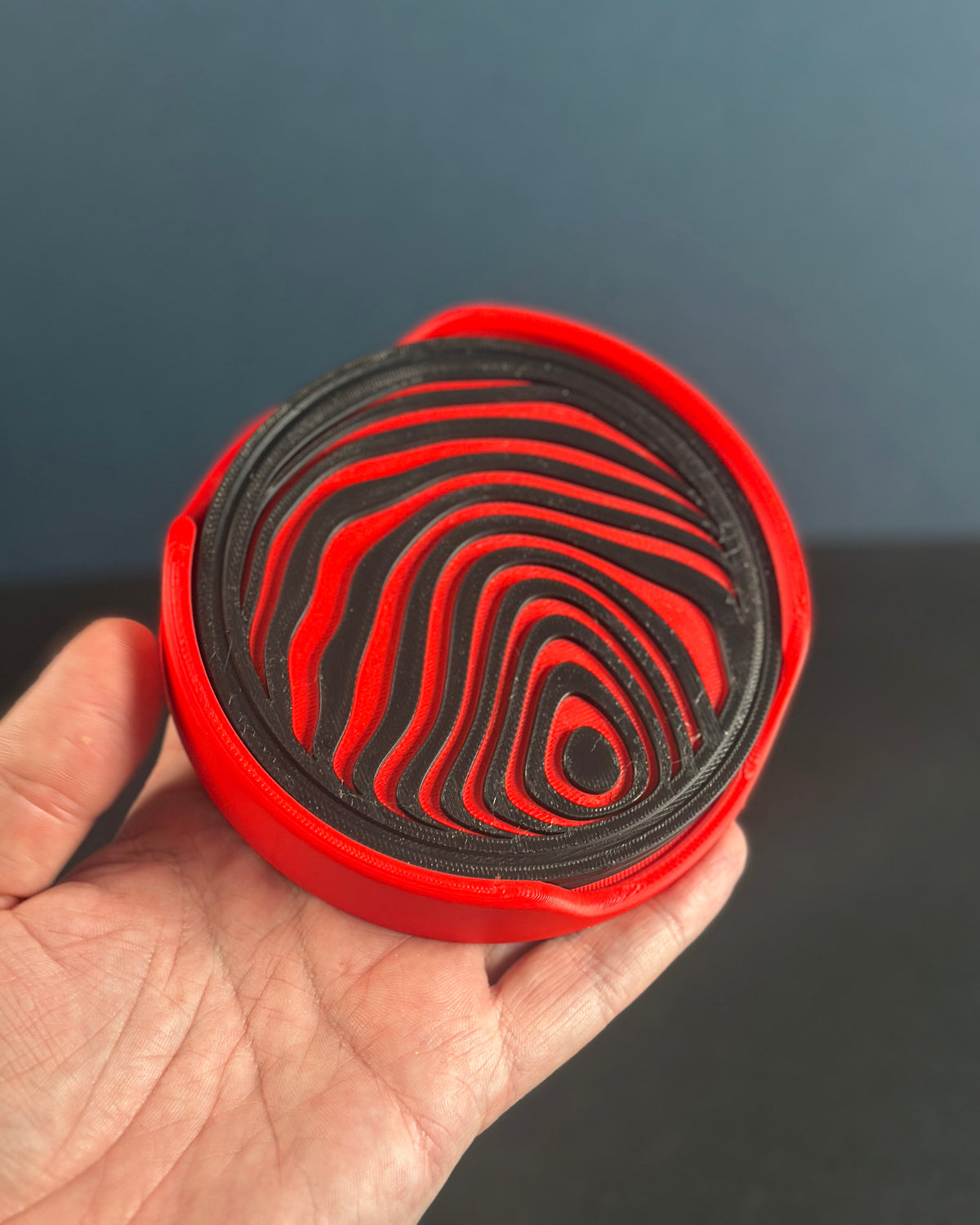 Red curved stand holding abstract sphere coasters
