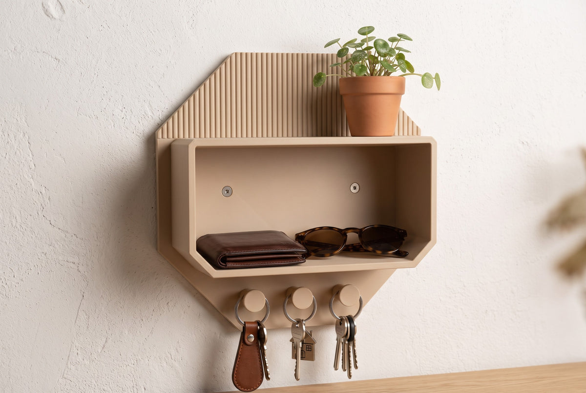 Octagonal beige wall shelf with a ribbed back panel, a plant on top, a wallet and sunglasses in the compartment and keys on three hooks