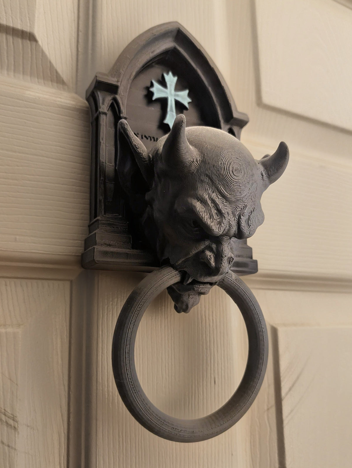Gargoyle door knocker mounted on panelled door angled view