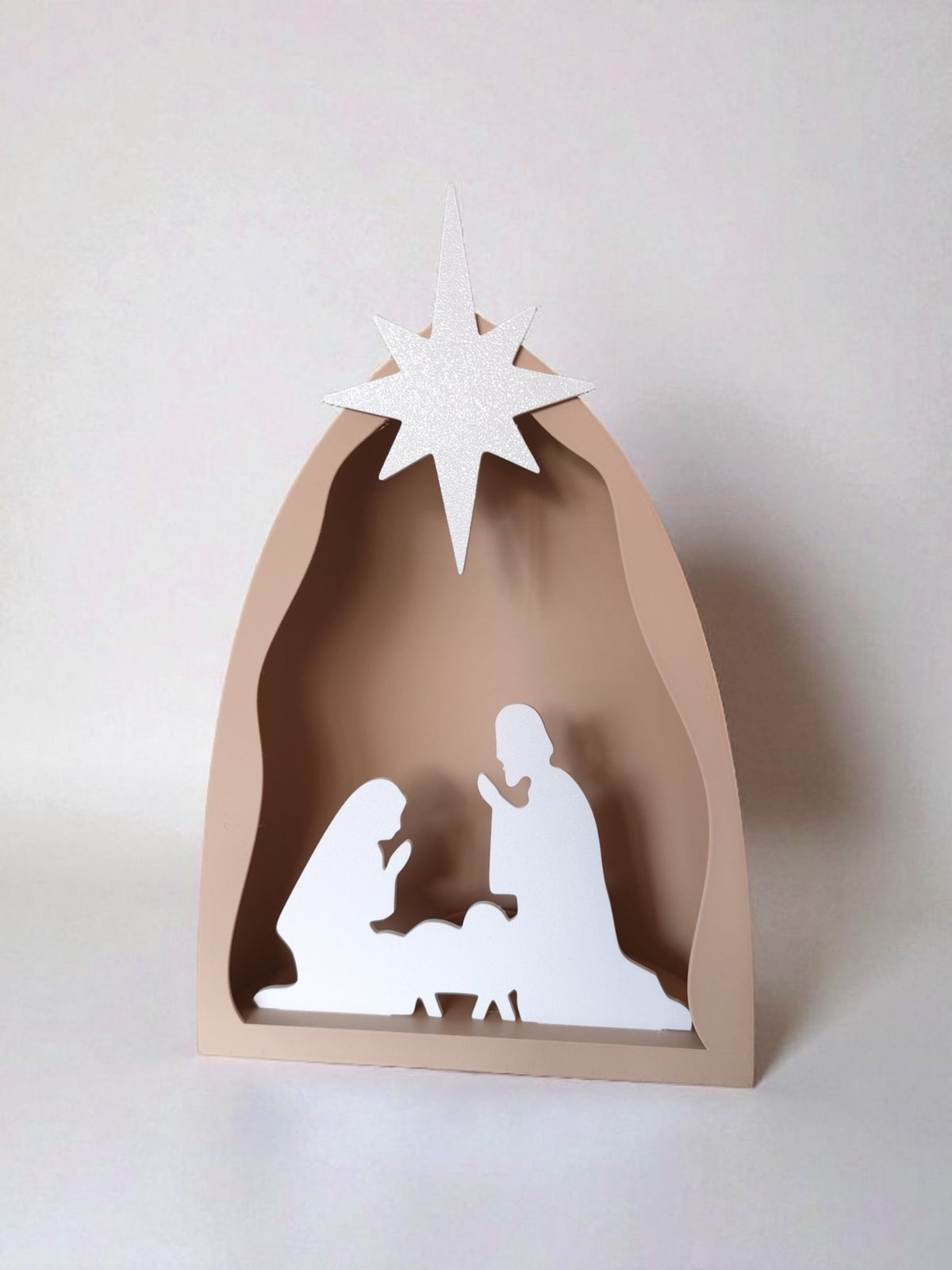 Illuminated nativity scene close-up on mantelpiece with fairy lights and pine cones