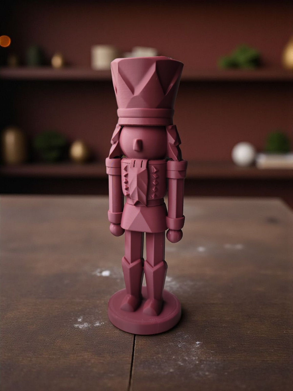 Dusty rose modern nutcracker on windowsill with pine sprig and fairy lights bokeh