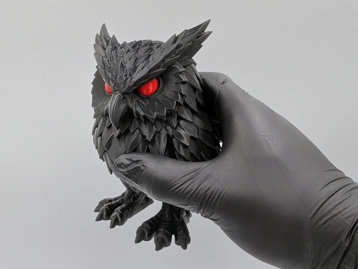 Crimson Watcher Owl held in hand for scale