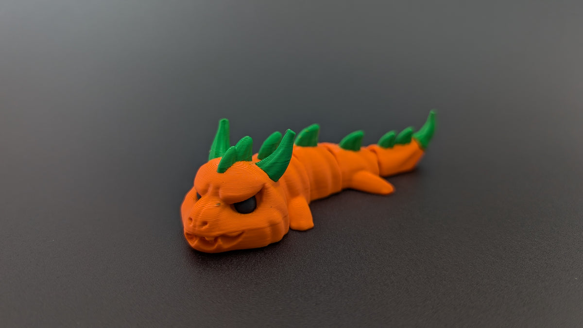 Orange articulated pumpkin dragon with green horns and spines