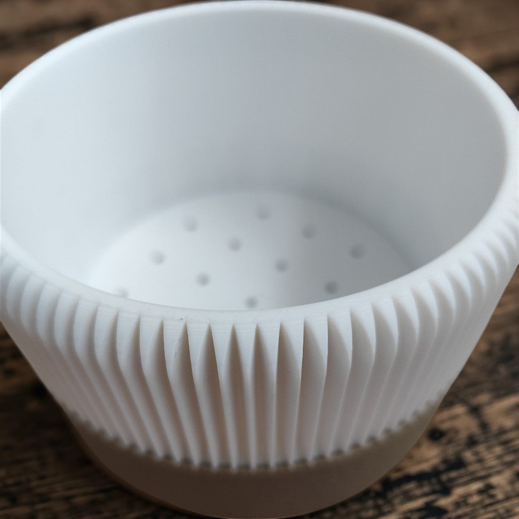 Close detail of vertical ribs on the white planter body and textured brown lower tray
