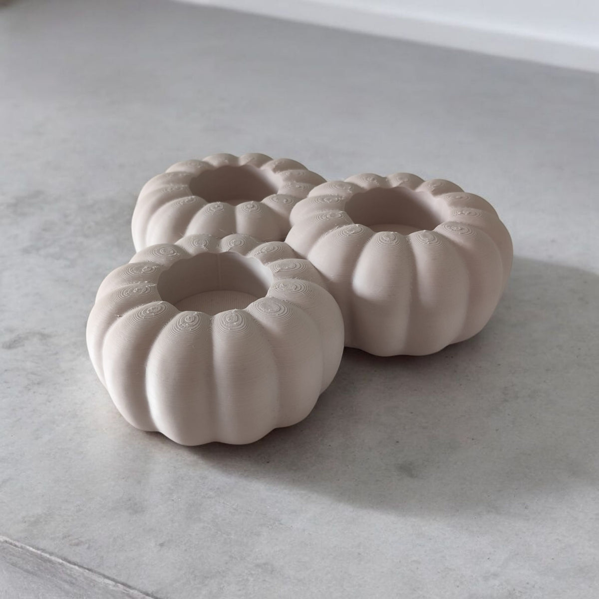 Three white ribbed pumpkin tealight holders with autumn leaves lifestyle shot