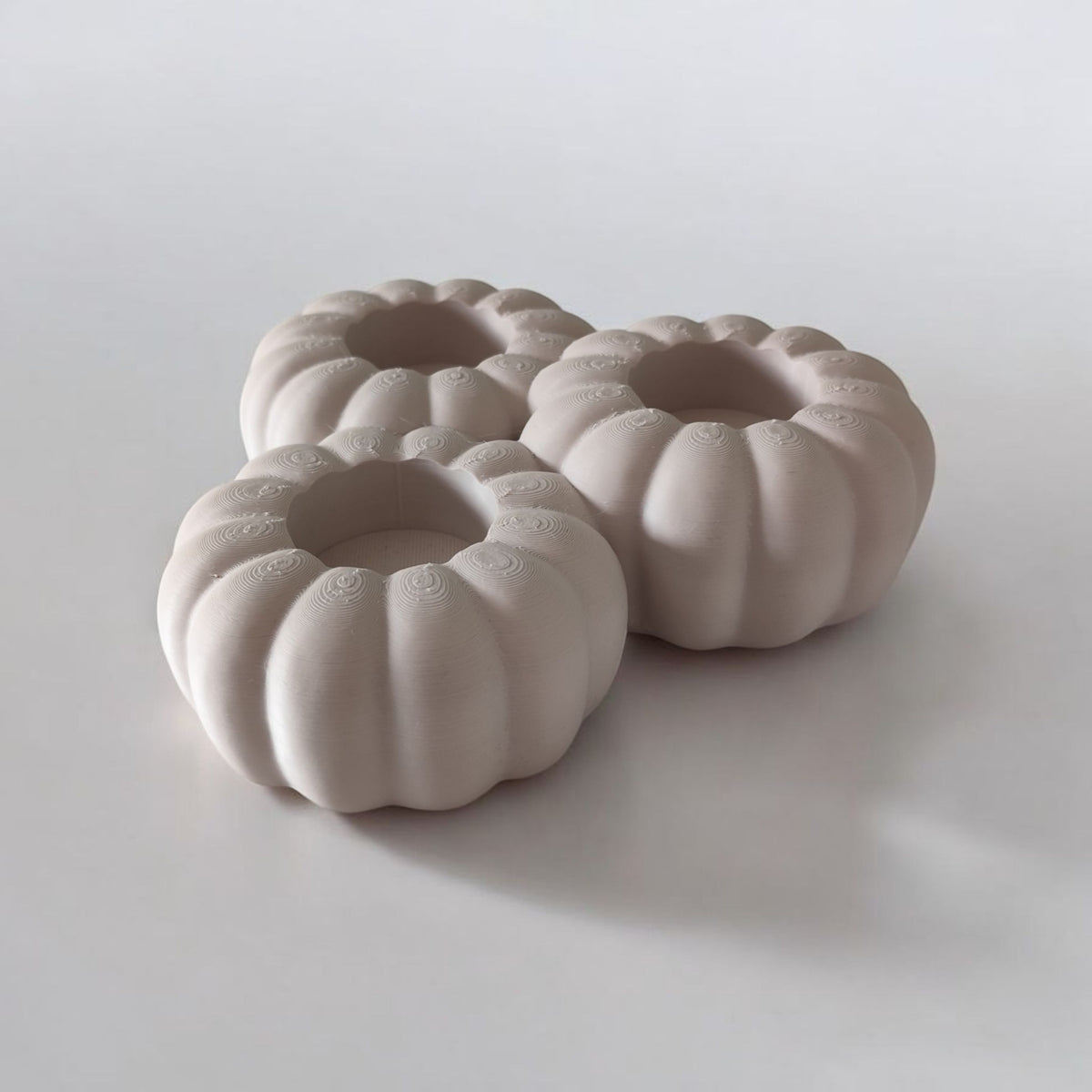 Three white ribbed pumpkin tealight holders low angle with dried branches