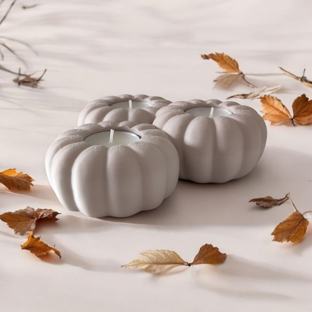 Three white pumpkin tealight holders on light oak table interior lifestyle