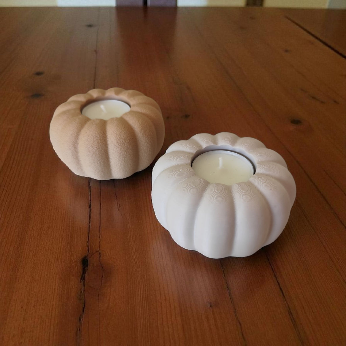 Two autumn pumpkin tealight holders beige and white on dark wood low angle lifestyle
