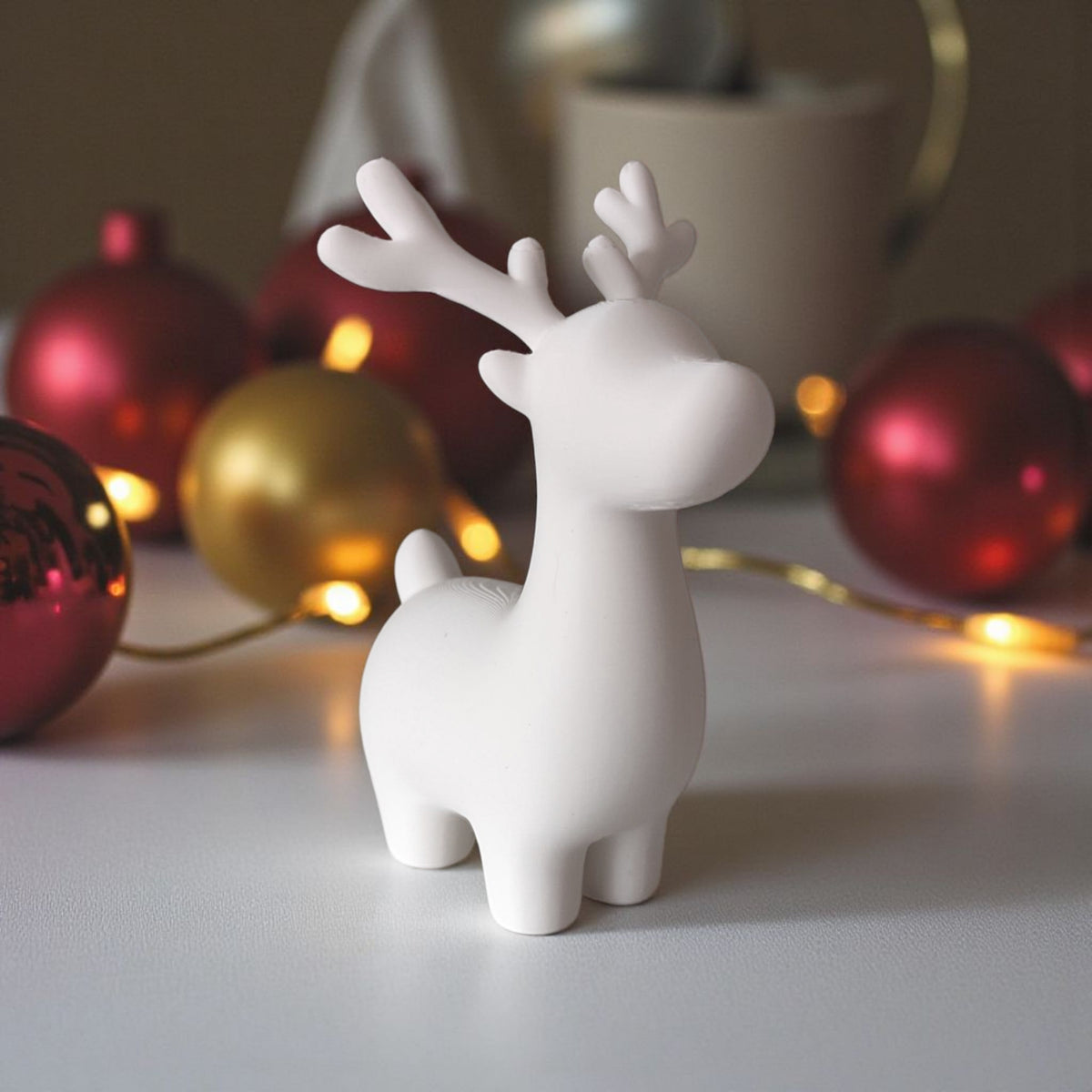 Grey and white reindeer pair on table with Christmas tree and fairy lights