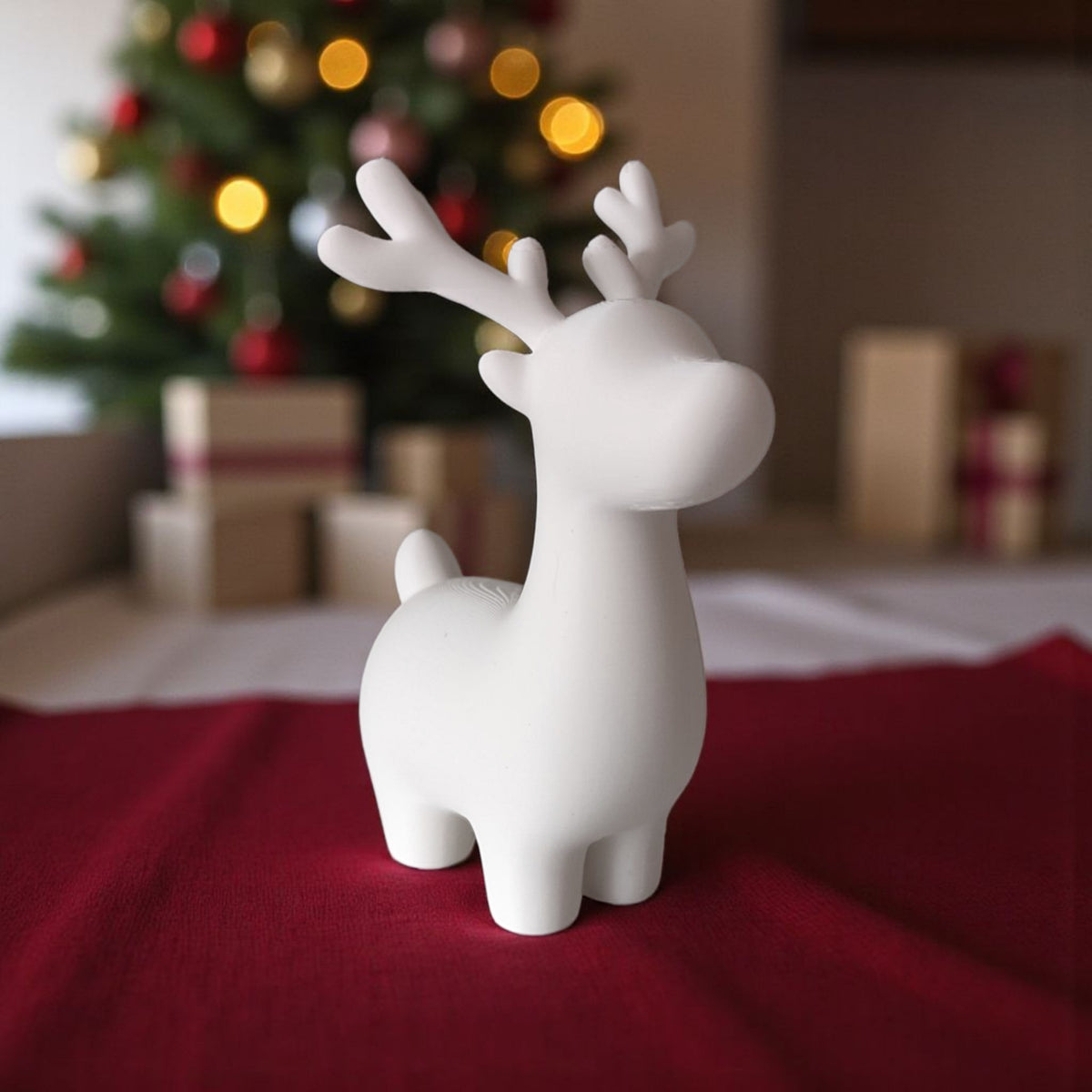 Grey and white reindeer pair on windowsill with pine cones and red bauble snowy view