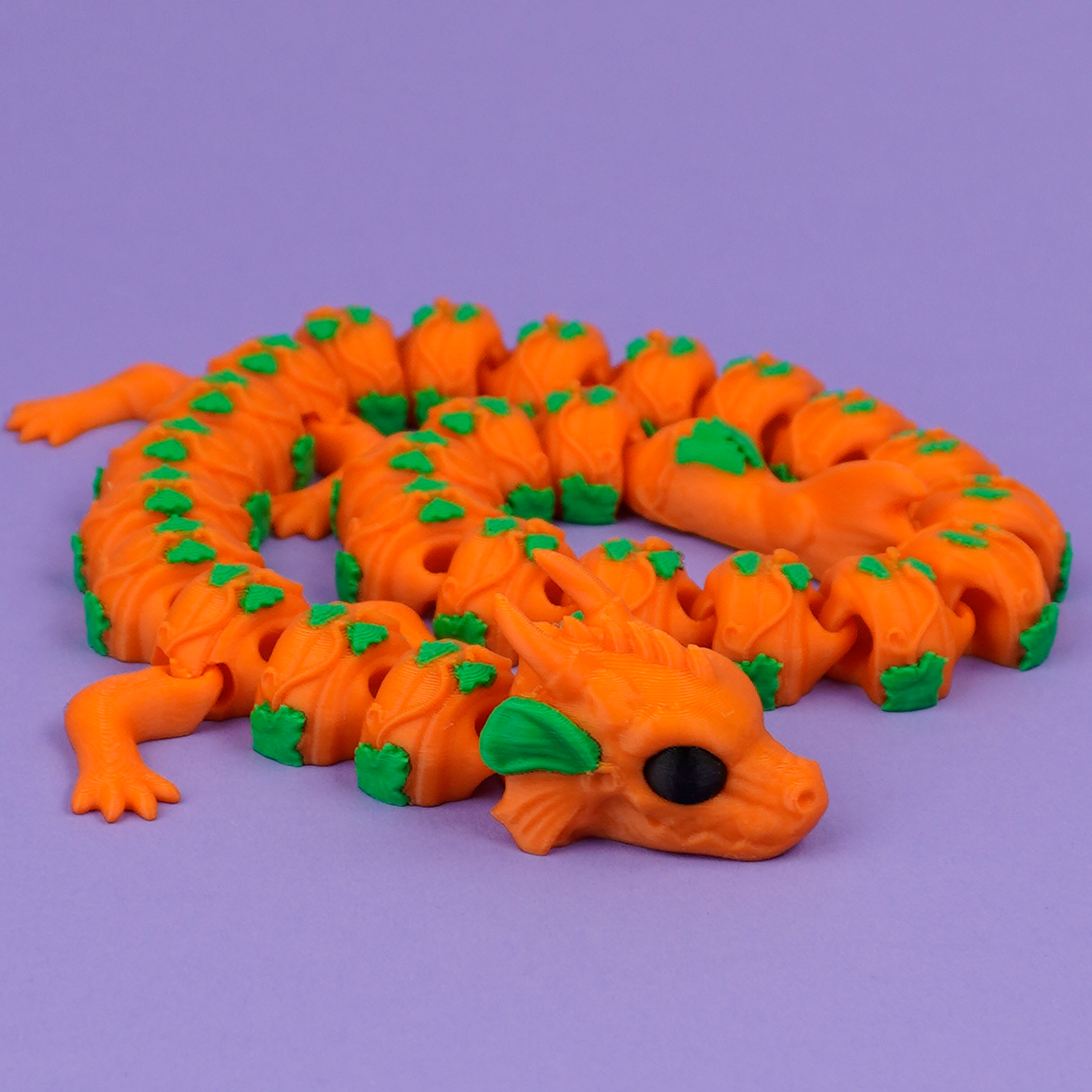Orange articulated Pumpkin Dragon curled on purple background