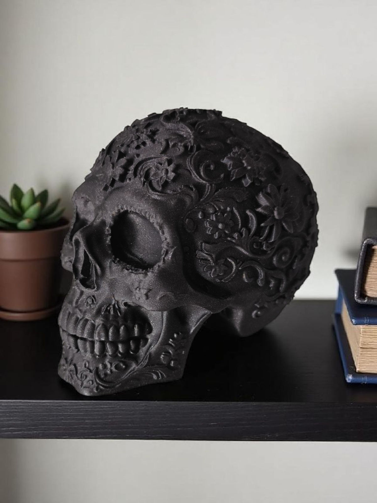 Matte black Mexican skull on dark wooden shelf with books lifestyle