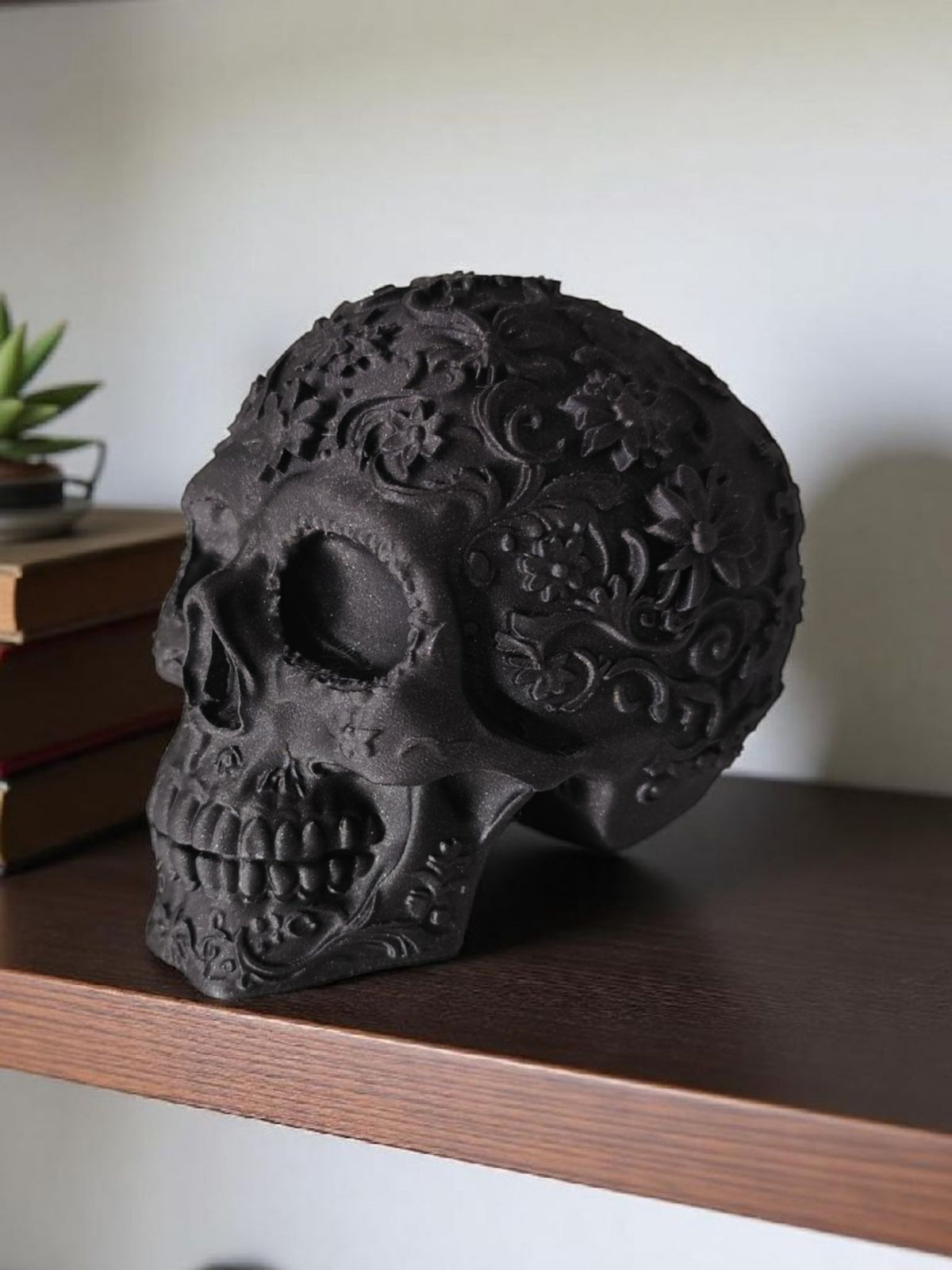 Matte black Mexican skull on dark wooden shelf with books and succulent lifestyle