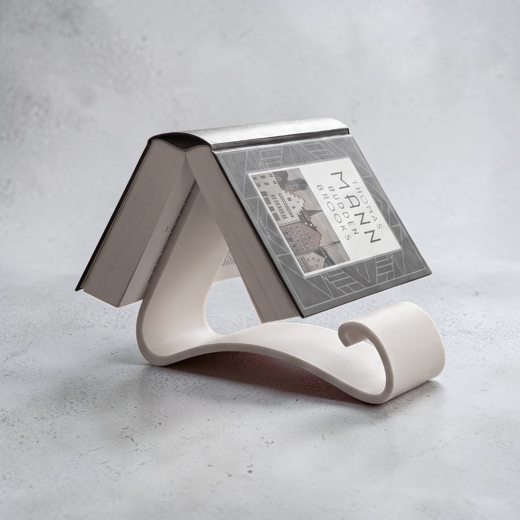 Wavy Book Stand in white holding a book upright on a wooden desk, full lifestyle view