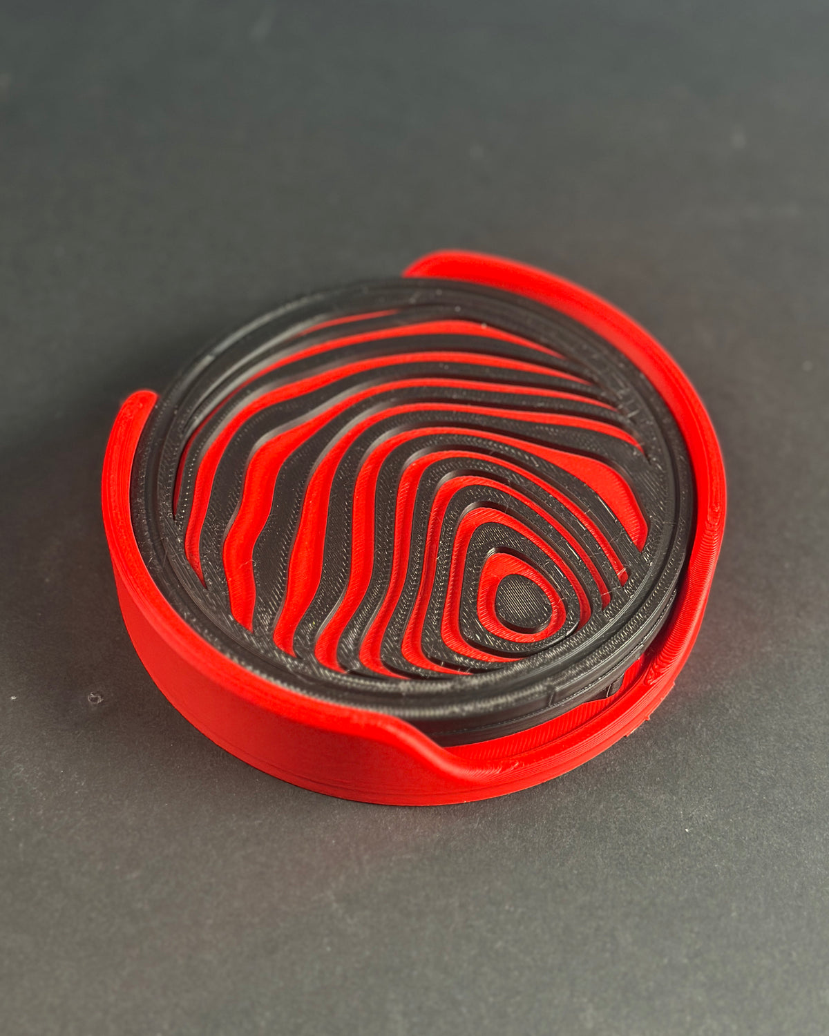 Red and black abstract sphere coasters in curved red stand