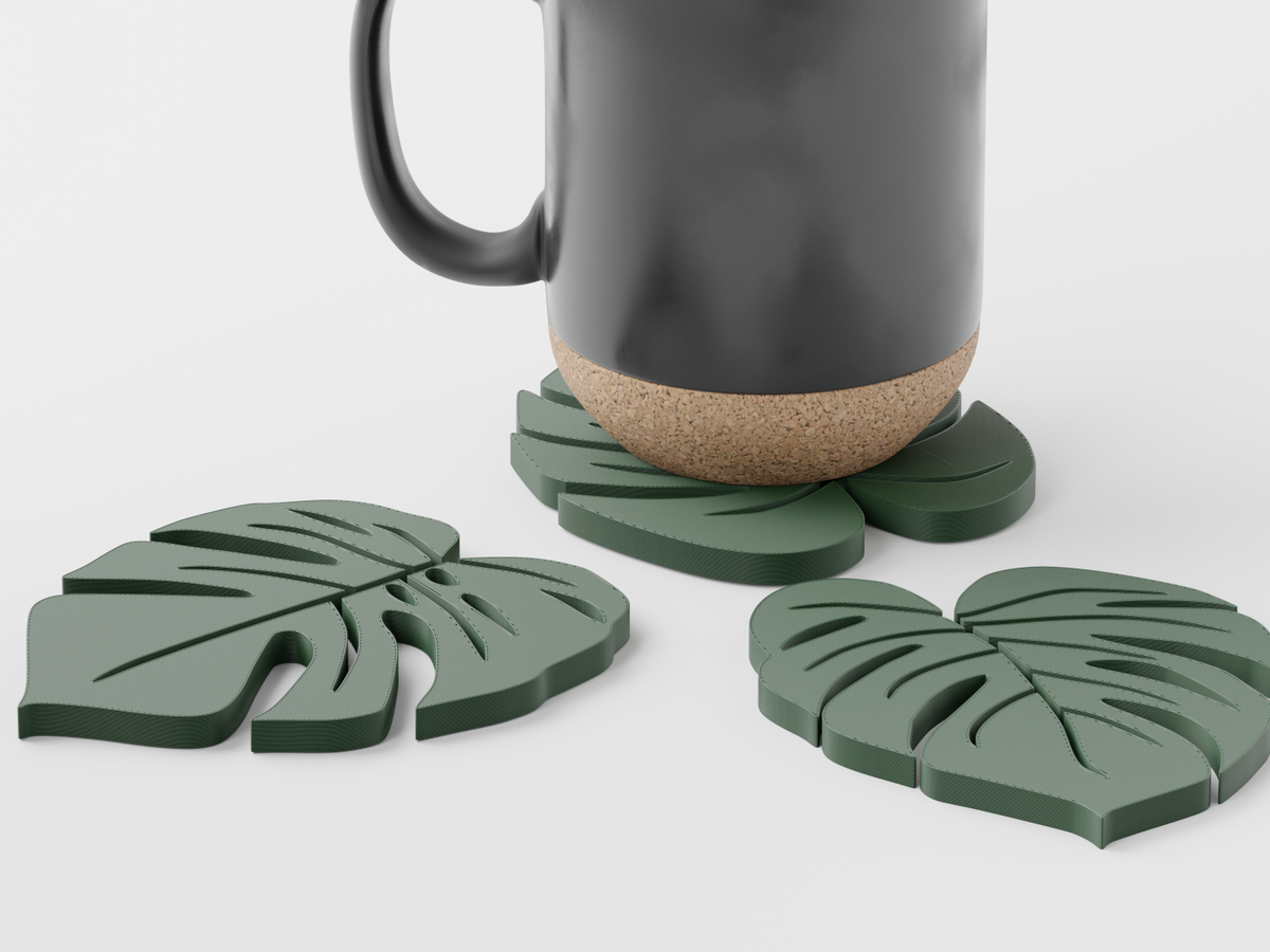 Sage green monstera leaf coasters with a black mug from above