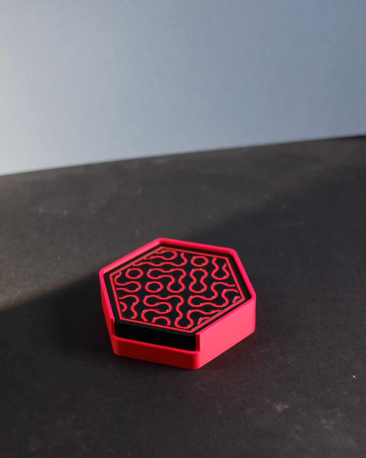Truchet coaster with black and pink pattern held in hands