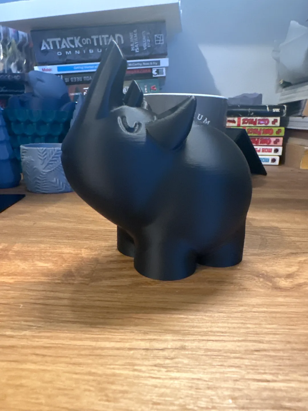 Dark grey Cute Rhino Figure displayed on a wooden desk beside books