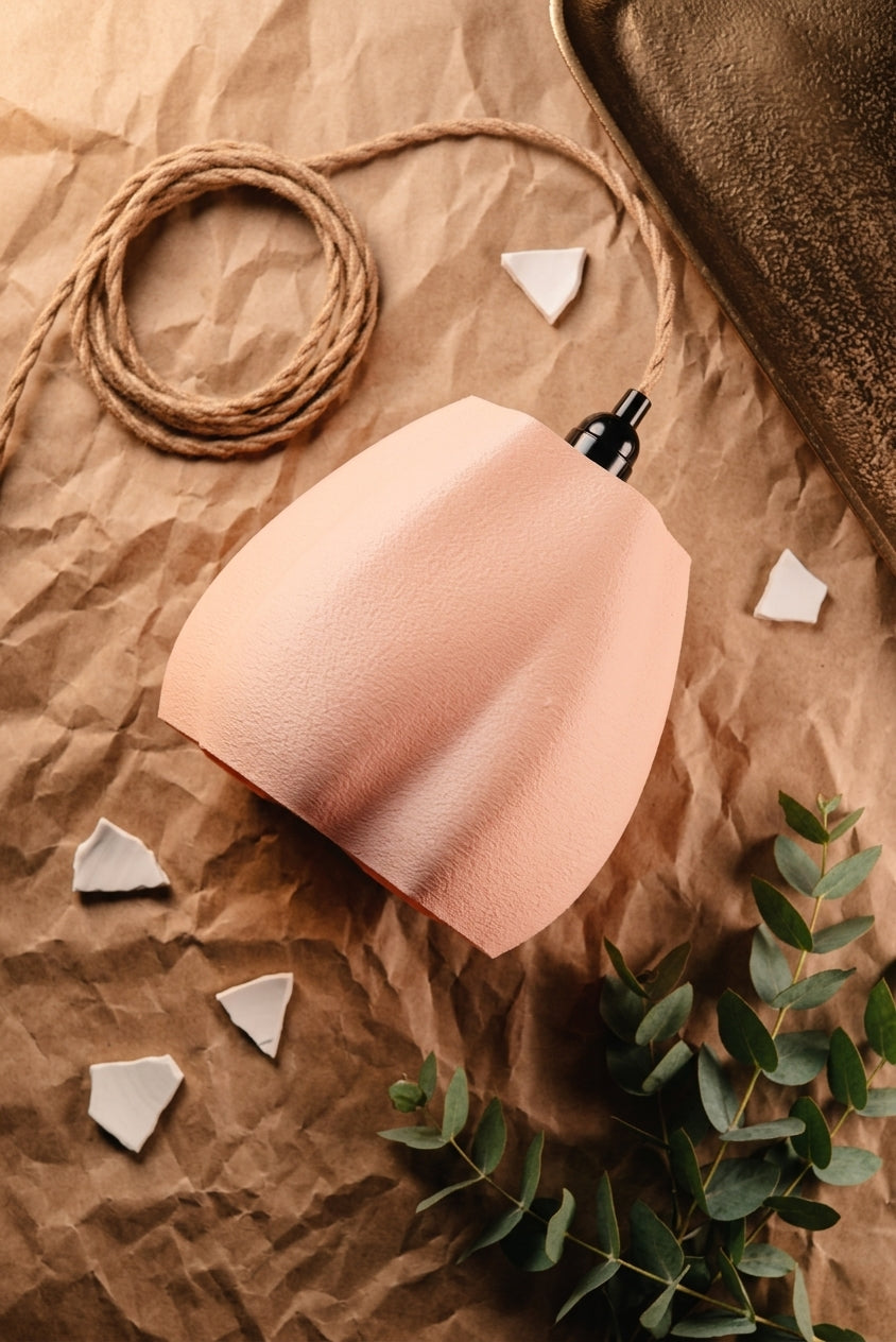 Organic flowing pendant lamp shade white hanging over draped linen table moody dark studio shot angled view