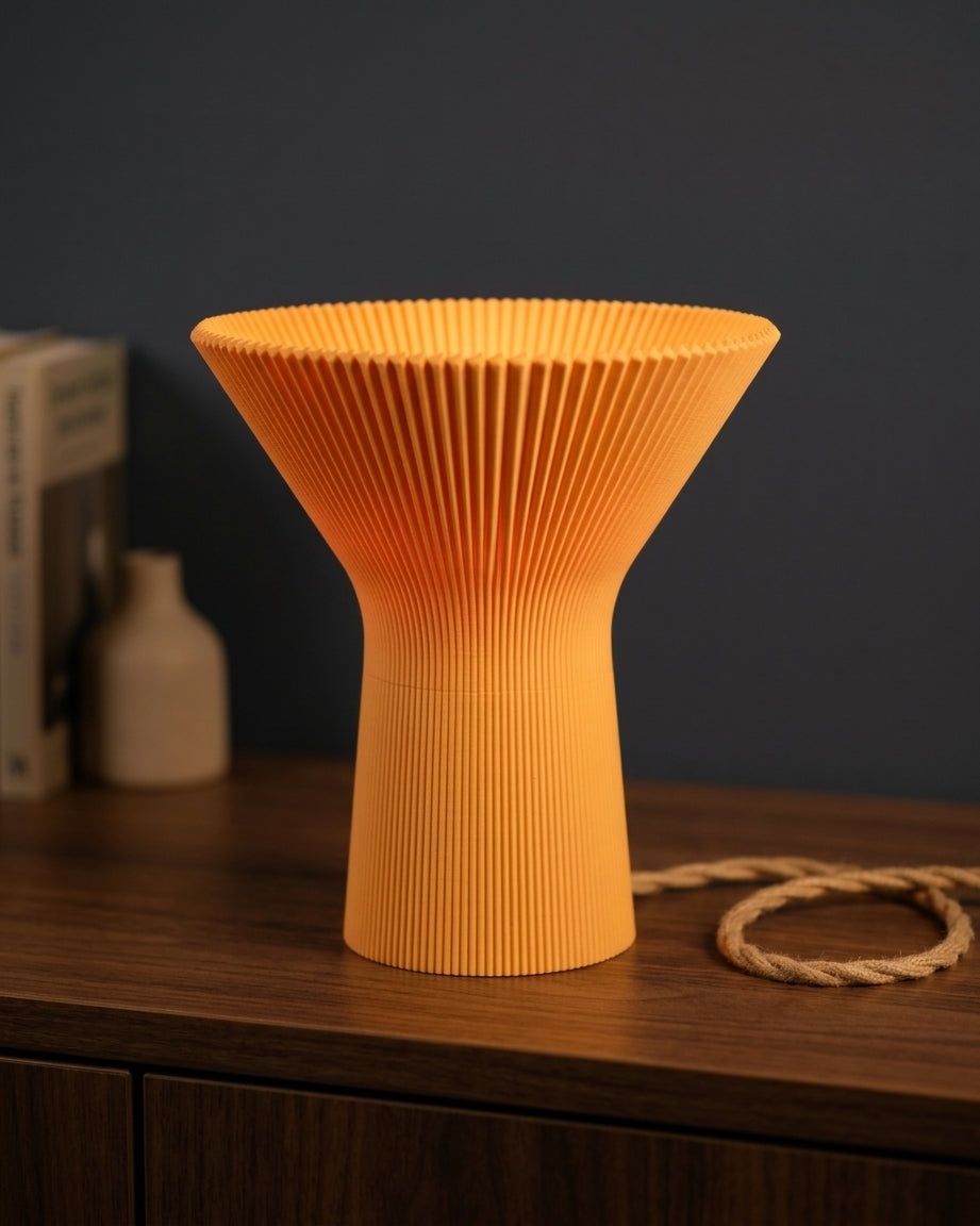 Orange pleated inverted funnel lamp shown against a dark background.