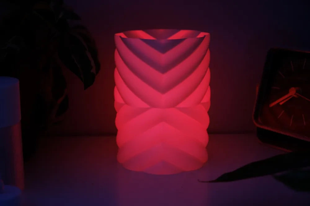 Geometric lampshade glowing red in a dark room