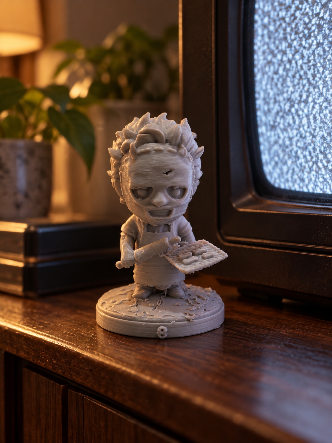 Unpainted eerie character figurine holding a board beside a television and houseplant
