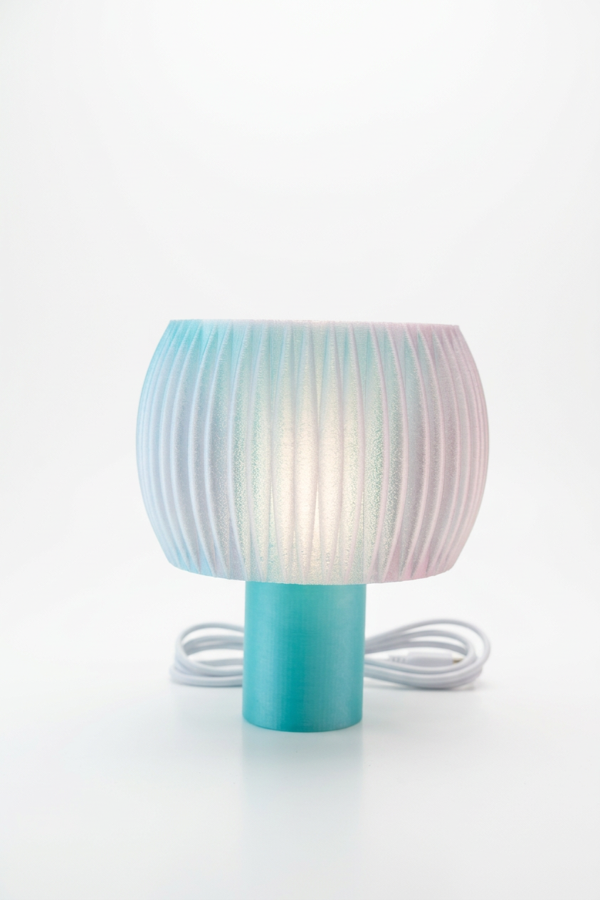 Elegant Funnel Glow Lamp white glowing shade teal base held hands dark background warm glow