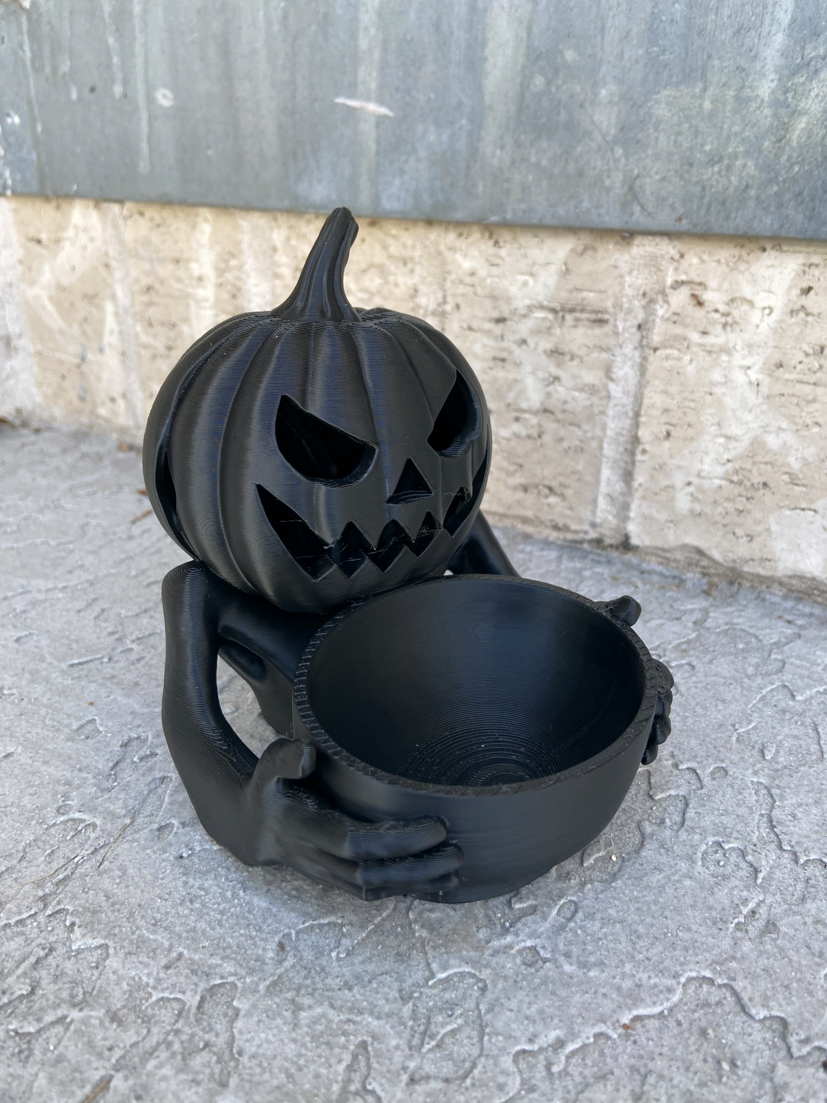 Black pumpkin figure holding an empty round tray
