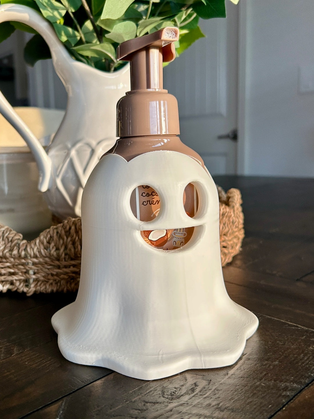 White ghost-shaped soap dispenser with brown pump on a dark vanity