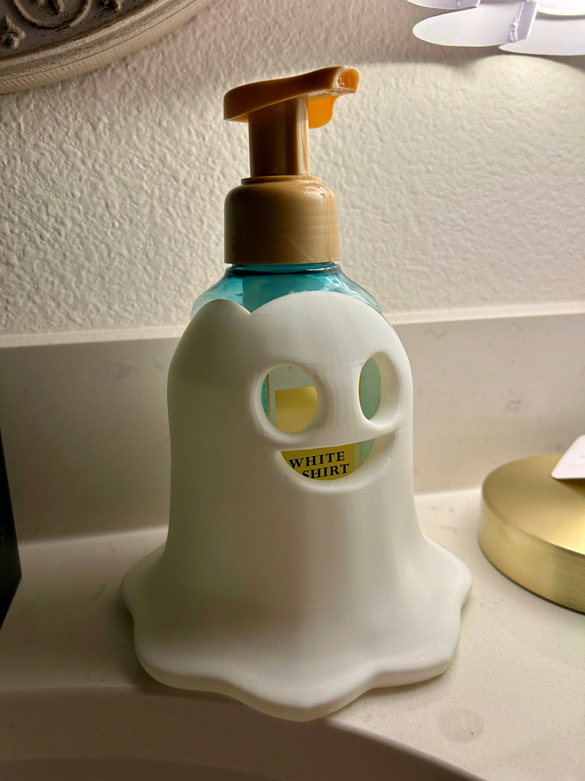 White ghost-shaped soap dispenser with turquoise collar and pale pump