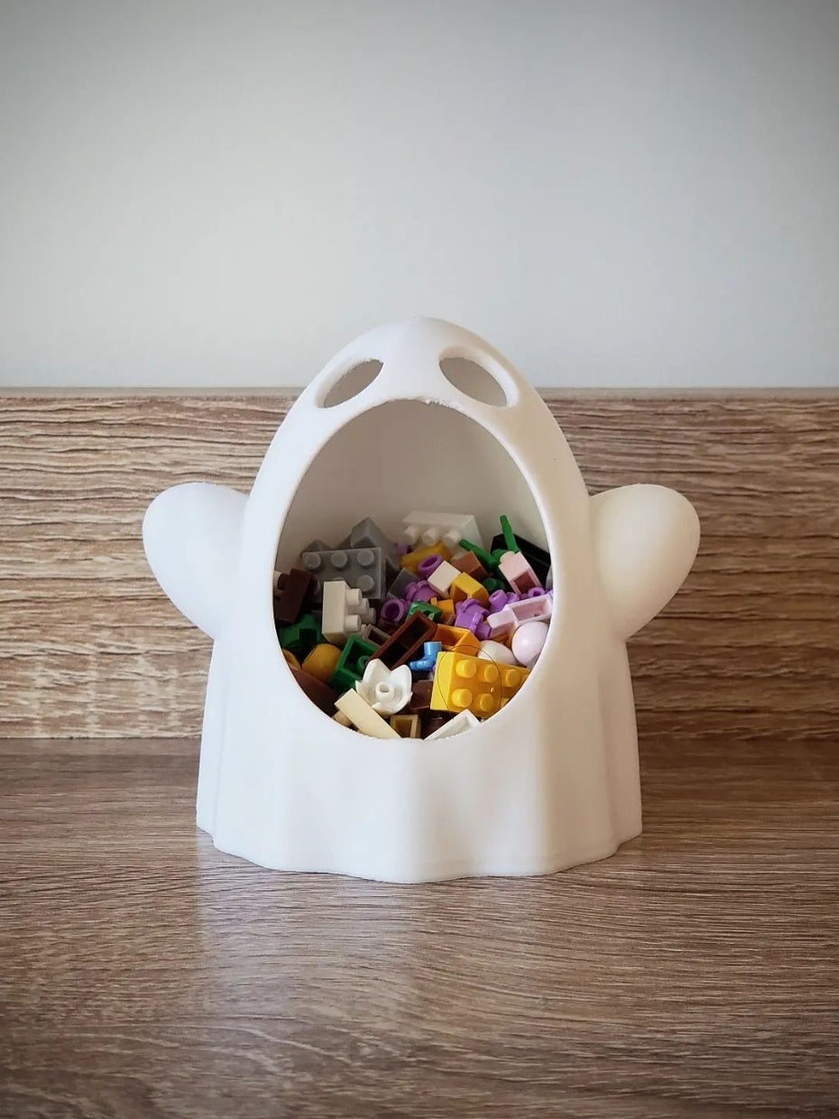 White wide-mouthed ghost sweet bowl filled with small colourful pieces on a wood tabletop, front view