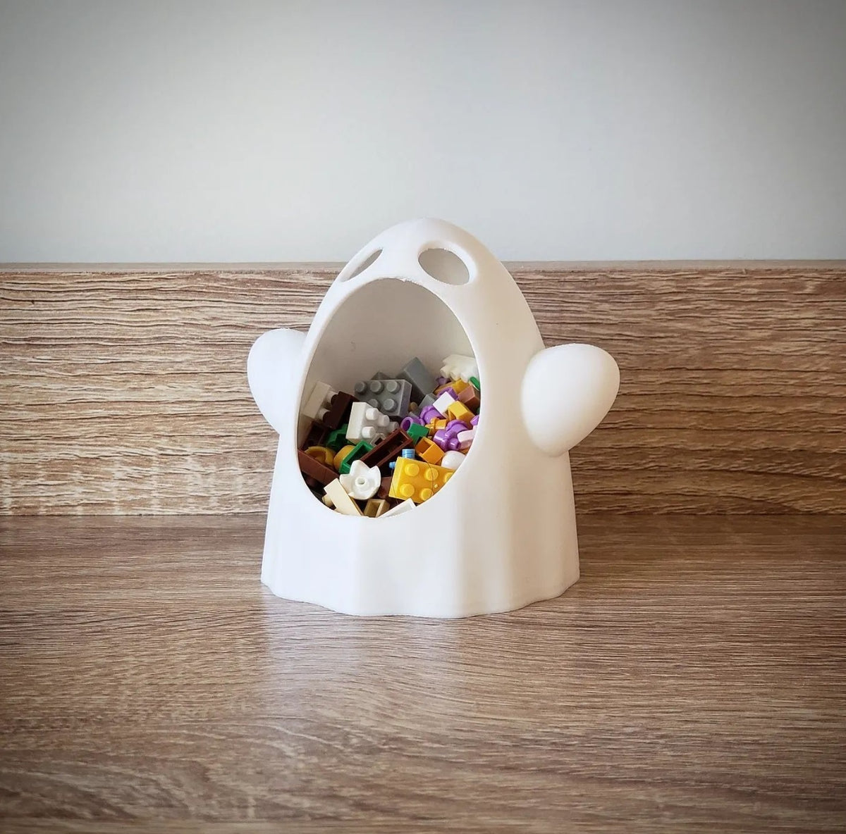White wide-mouthed ghost sweet bowl with wide open mouth on a wood tabletop, front angled view