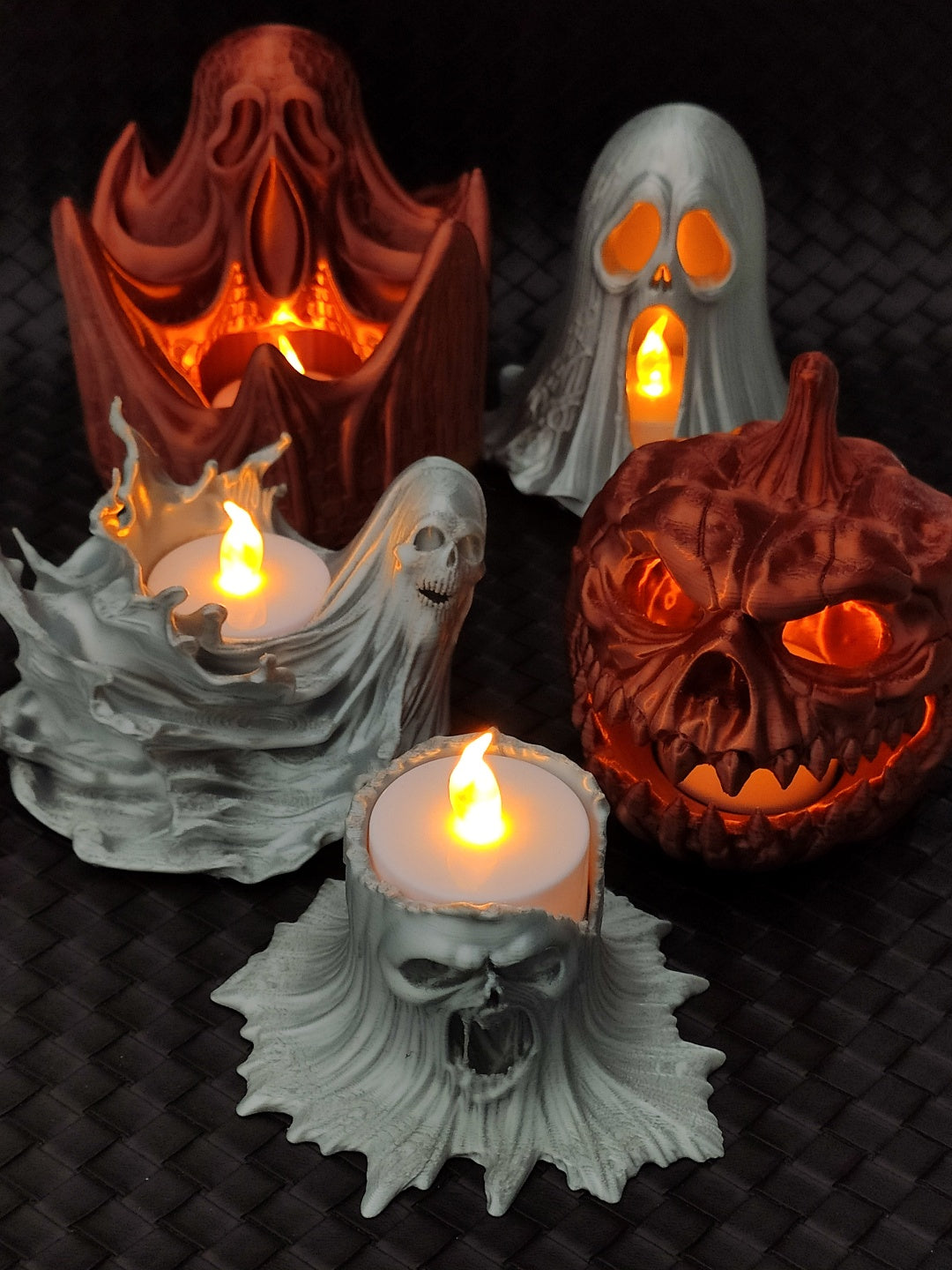 Five different horror tealight holders displayed together, including ghosts, skulls, a pumpkin skull and a gothic archway