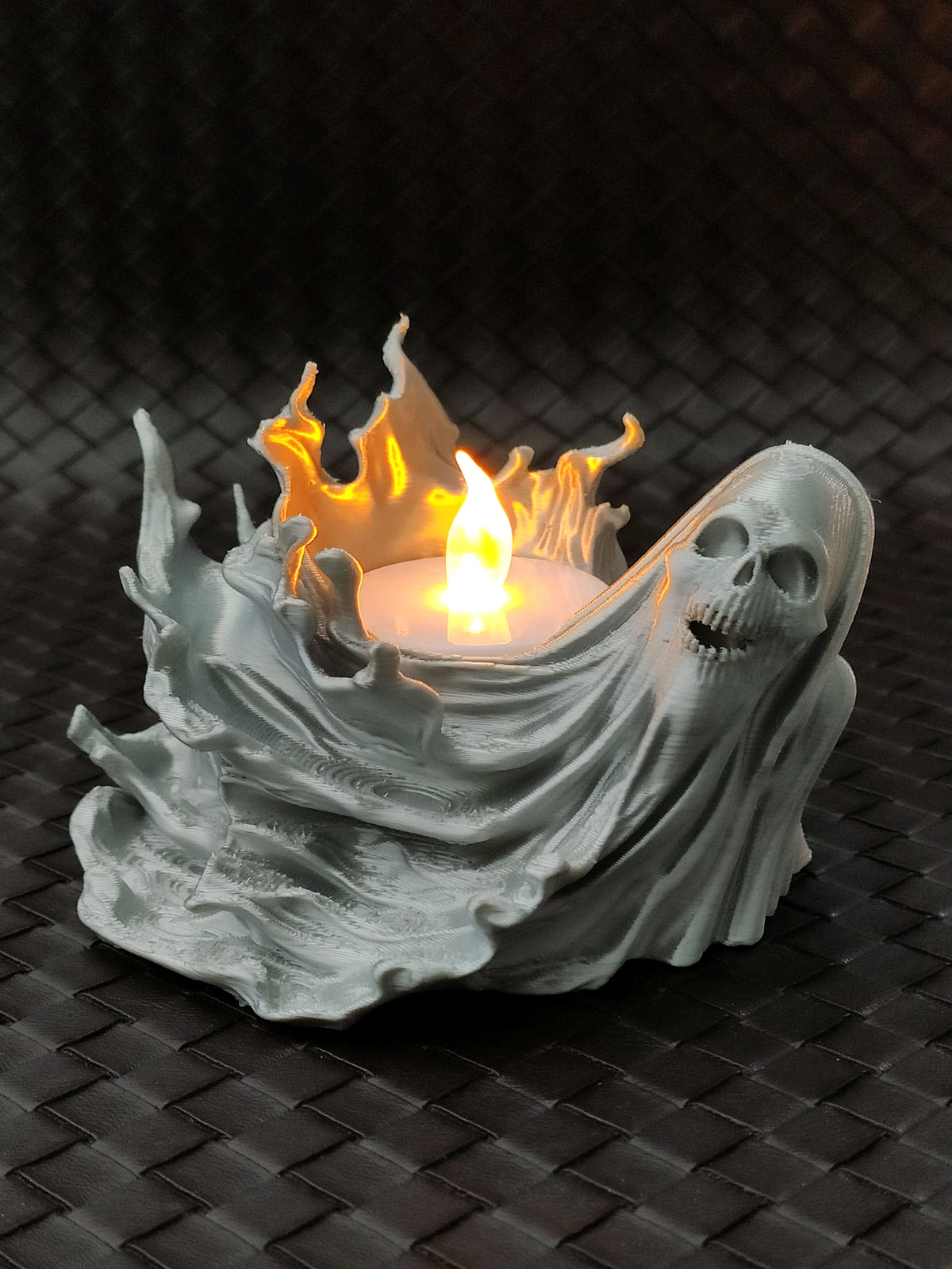 Pale flowing ghost-shaped tealight holder with a small skull detail and a warm glowing light