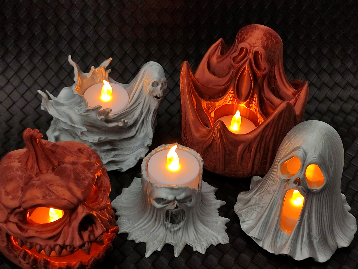 Grey skull-faced tealight holder with a candle cup at the top and warm glowing light