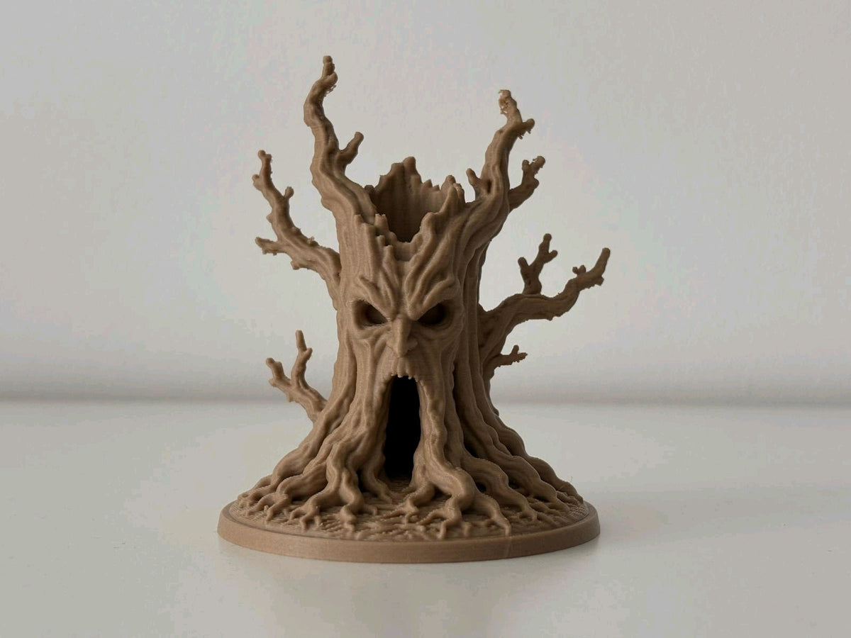 Brown haunted tree tealight holder glowing through its face and hollow trunk against a light background