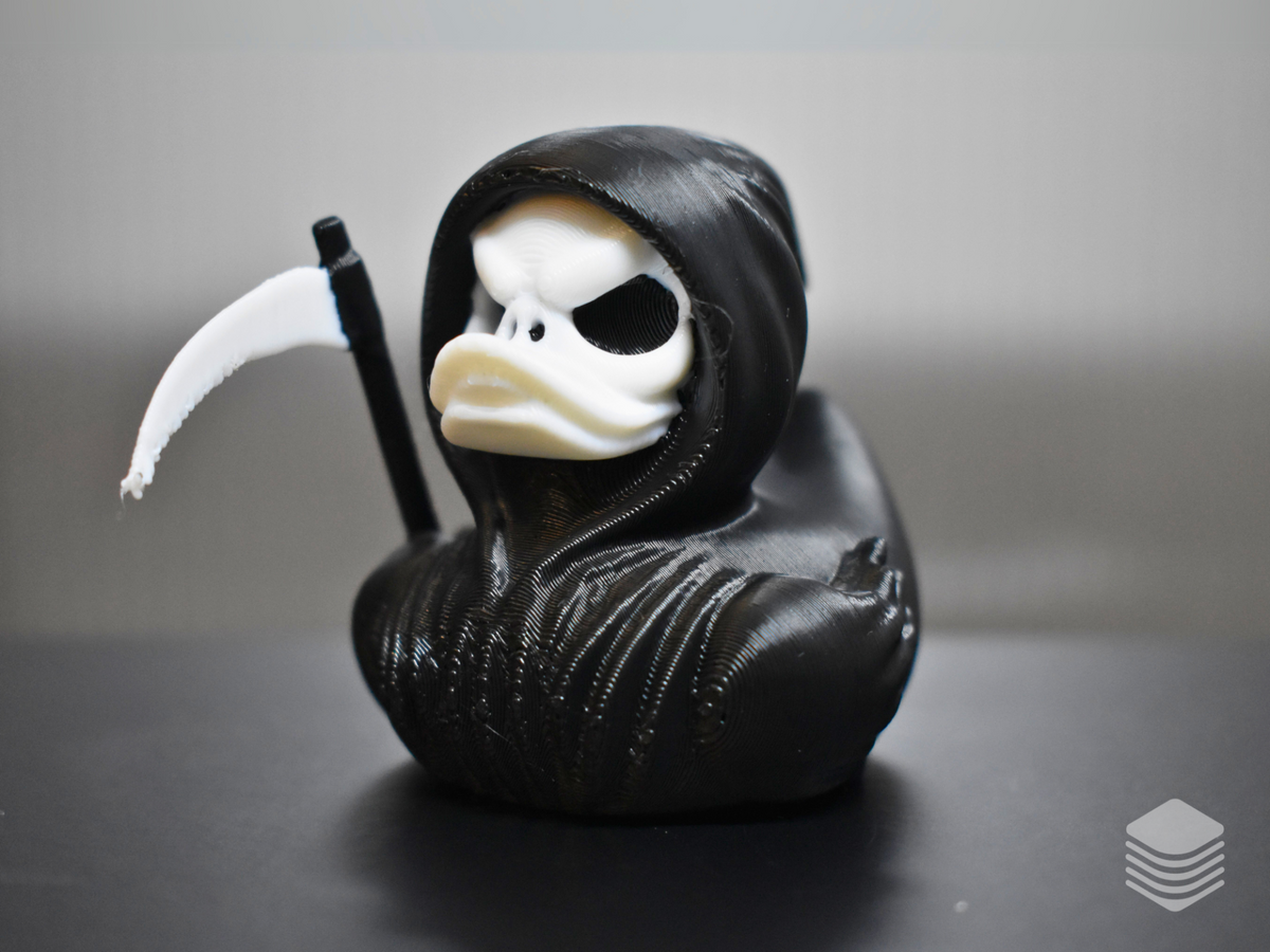 Black-and-white Grim Reaper bath duck with hood, skeletal face and scythe
