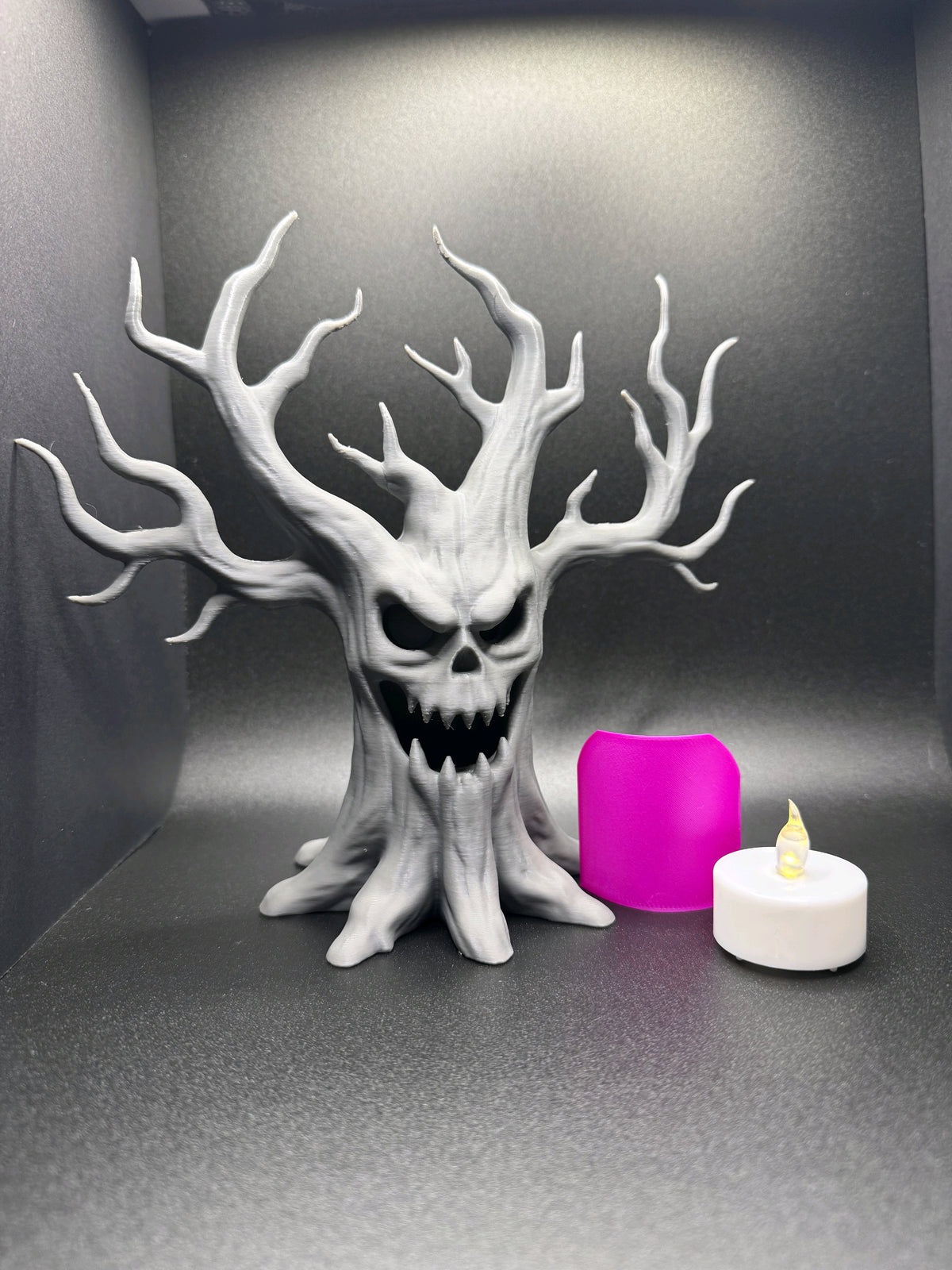 Grey laughing tree tealight holder shown with a battery LED tealight