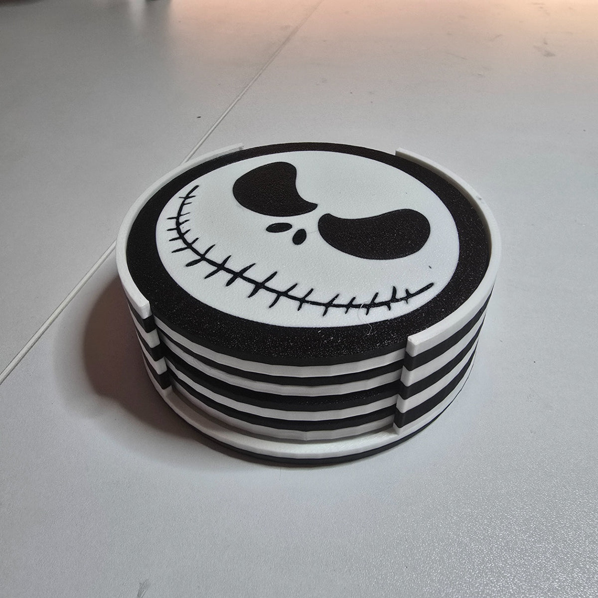 Stacked black-and-white character coasters with striped edges