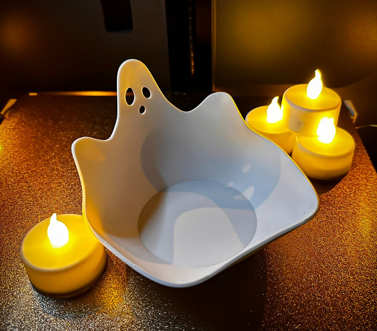 Empty white ghost-shaped open-top sweet tray beside warm decorative lights